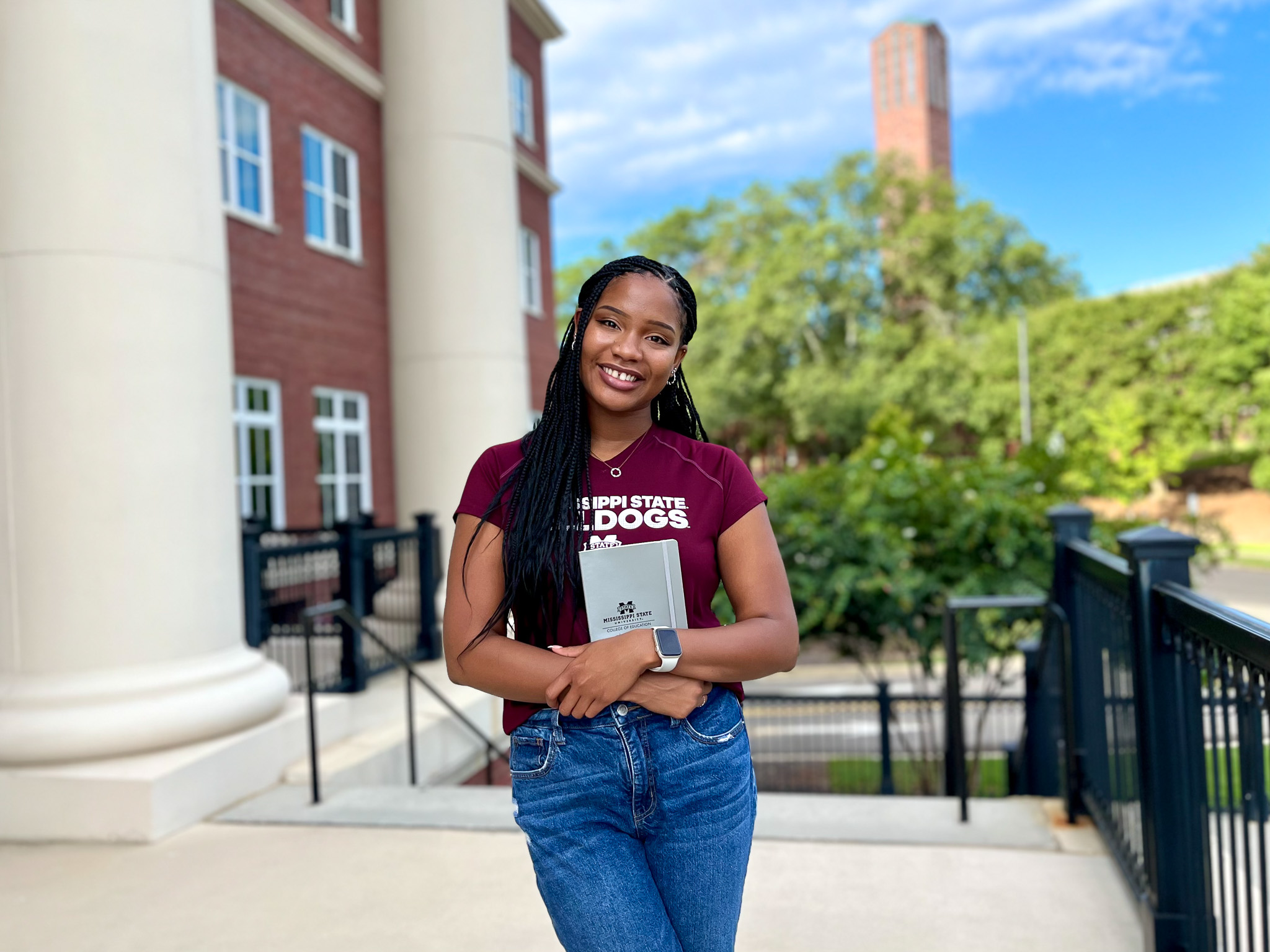 Student holding notebook while standing outside a building 